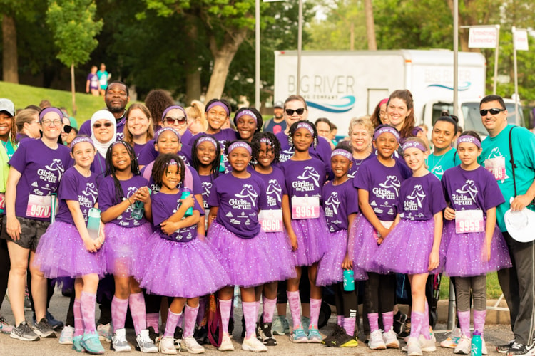 Group of GOTR participants in purple shirts and purple tutus smiling together before the race