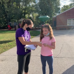 Girls on the run coach handing out activity card to participant