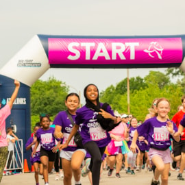 Girls on the Run participants taking off at the starting line of the 5K